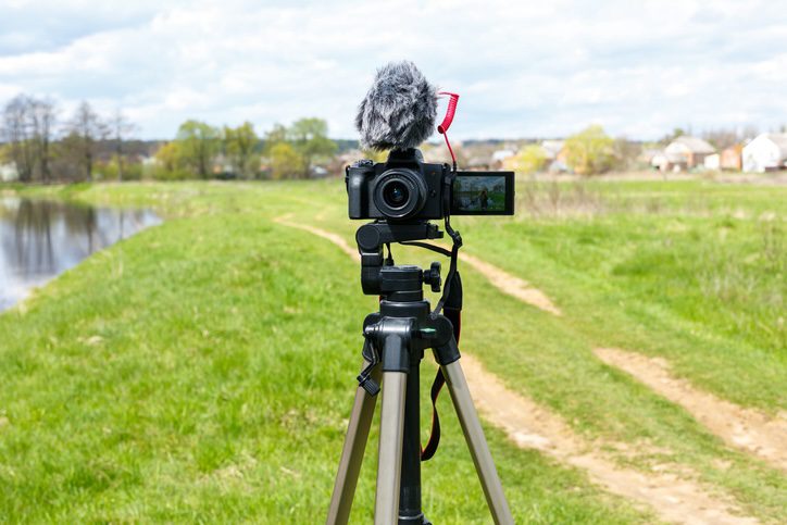 Behind the scene concept. Cameraman working on professional camera taking TV interviewer, professional news reporter making news outdoors.